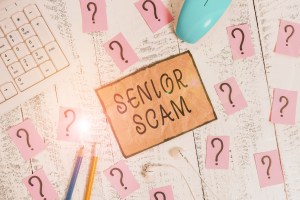 Conceptual hand writing showing Senior Scam. Business photo showcasing fraud schemes targeting the lifestyle and savings of the elderly Writing tools and scribbled paper on top of the wooden table.